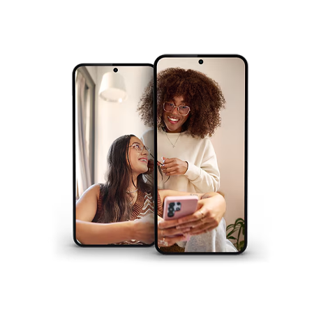 Two women smiling while looking at a smartphone, representing Bell Mobility offers.